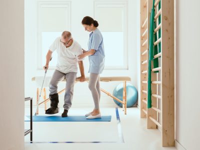 Young physiotherapist exercises in a bright medical office with his injured patient